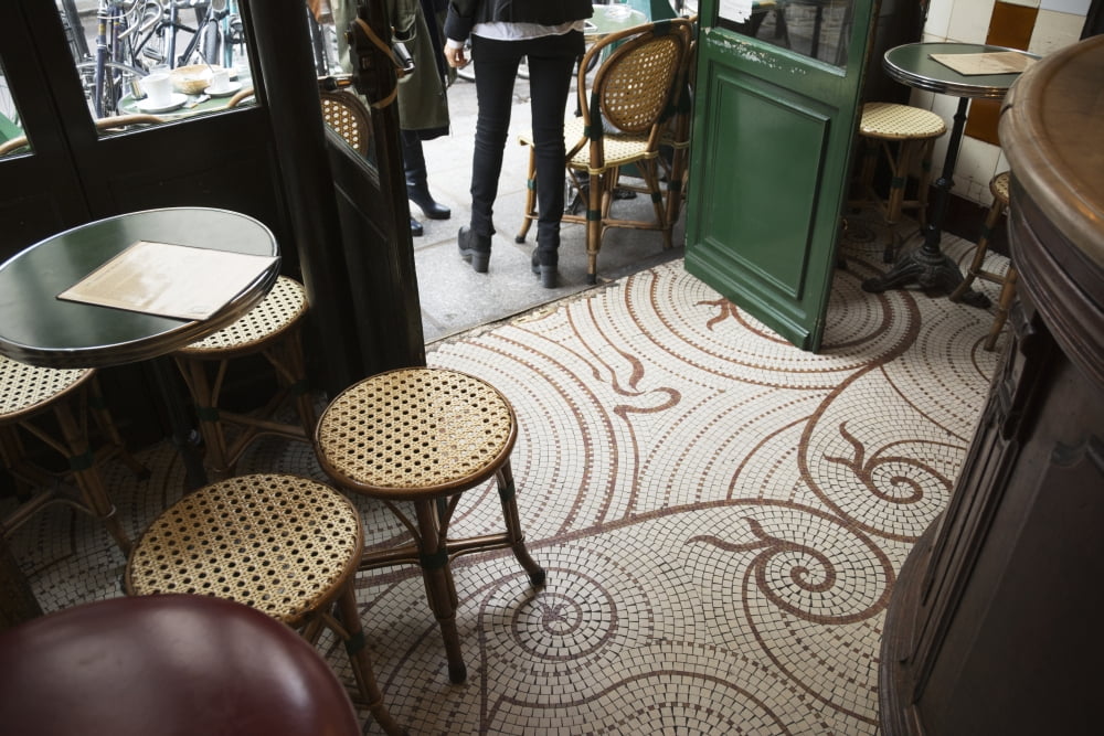 Looking down at the floor of a parisian cafe with small square tiles traditional tables and stools and the wooden bar Paris France Canvas Art - Philippe Widling Design Pics (19 x 12)