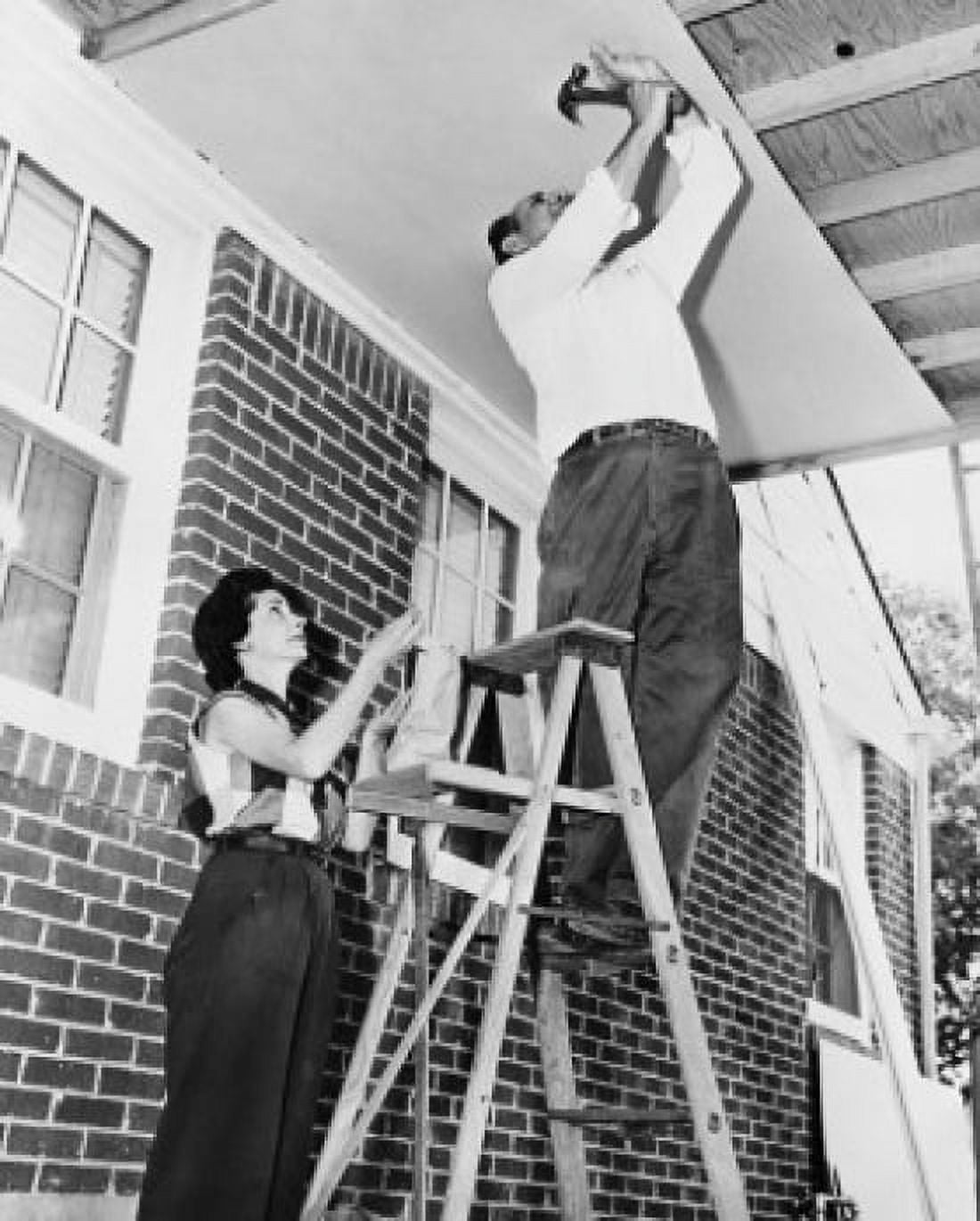 Low angle view of a mid adult man fixing plywood on a porch with a mid adult woman helping him Canvas Art - (24 x 36)