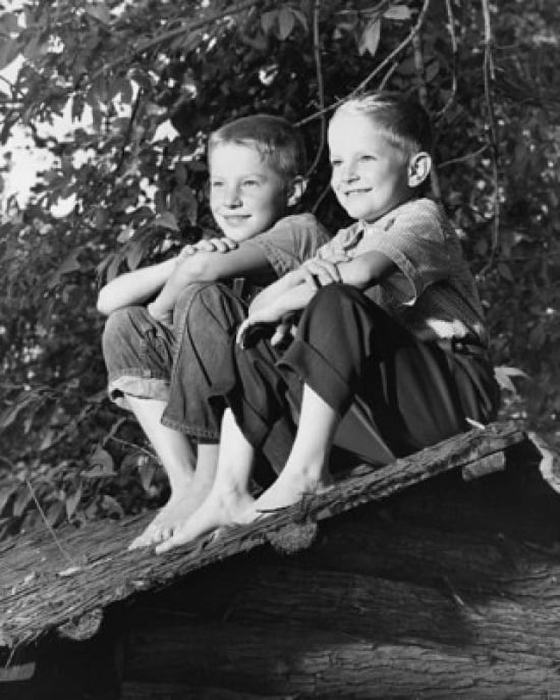 Low angle view of two boys sitting on a thatched roof Canvas Art - (18 x 24)
