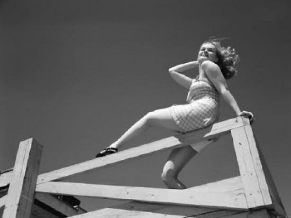Low angle view of woman sitting on wooden fence Canvas Art - (24 x 36)