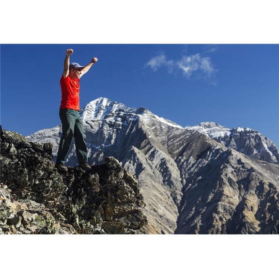 Male Hiker Standing with Arms Raised in The Air On Top of Mountain Ridge Overlooking Snow Peaked Mountains with Blue Sky Poster Print by Michael Interisano - 36 x 24 - Large