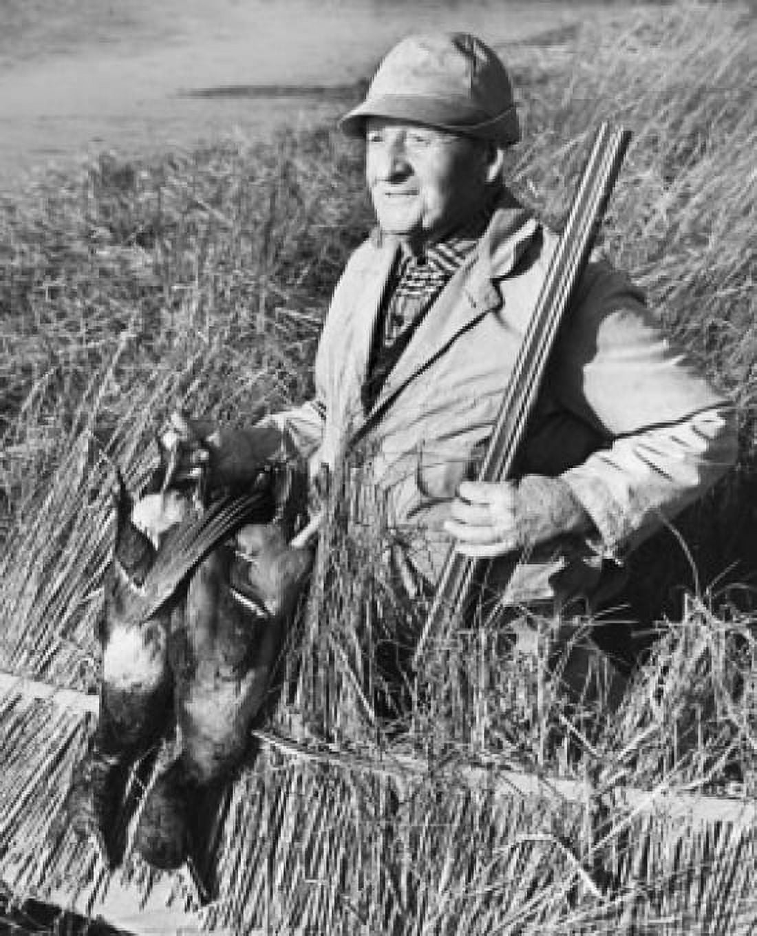 Male hunter holding two dead ducks and a rifle in a field Canvas Art - (24 x 36)