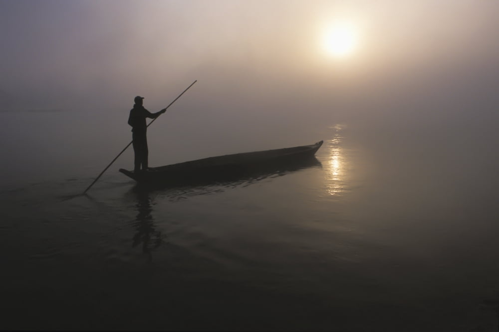 A Man Pushes His Dugout Canoe Along The Rapti River Near Sauraha And Chitwan National Park At Dawn Nepal Canvas Art - Sean White Design Pics (19 x 12)