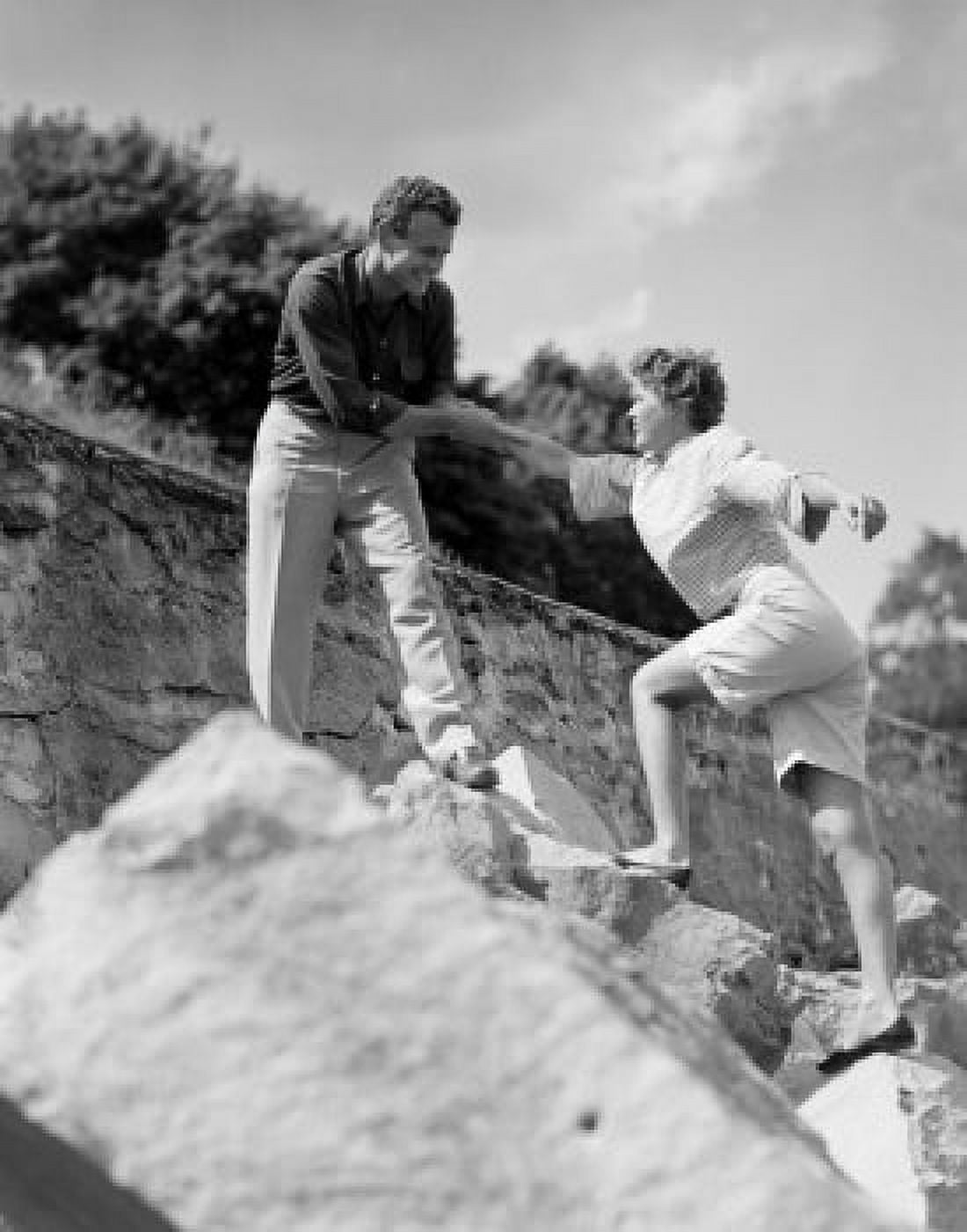 Man assisting woman climbing on rock Canvas Art - (24 x 36)