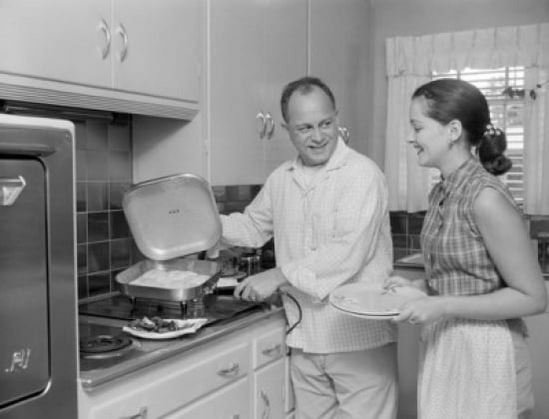 Man holding pan with food in the kitchen woman waiting with plates Canvas Art - (24 x 36)