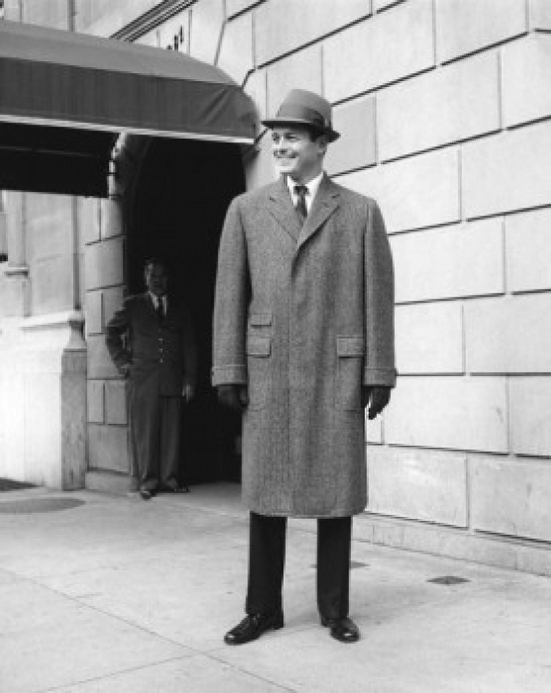 Man in coat and hat standing in front of hotel Canvas Art - (18 x 24)
