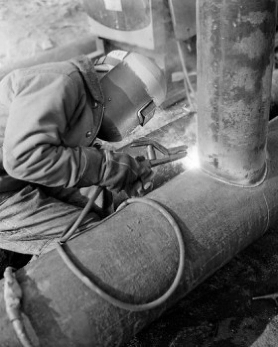 Man in welding mask welding pipe Canvas Art - (18 x 24)