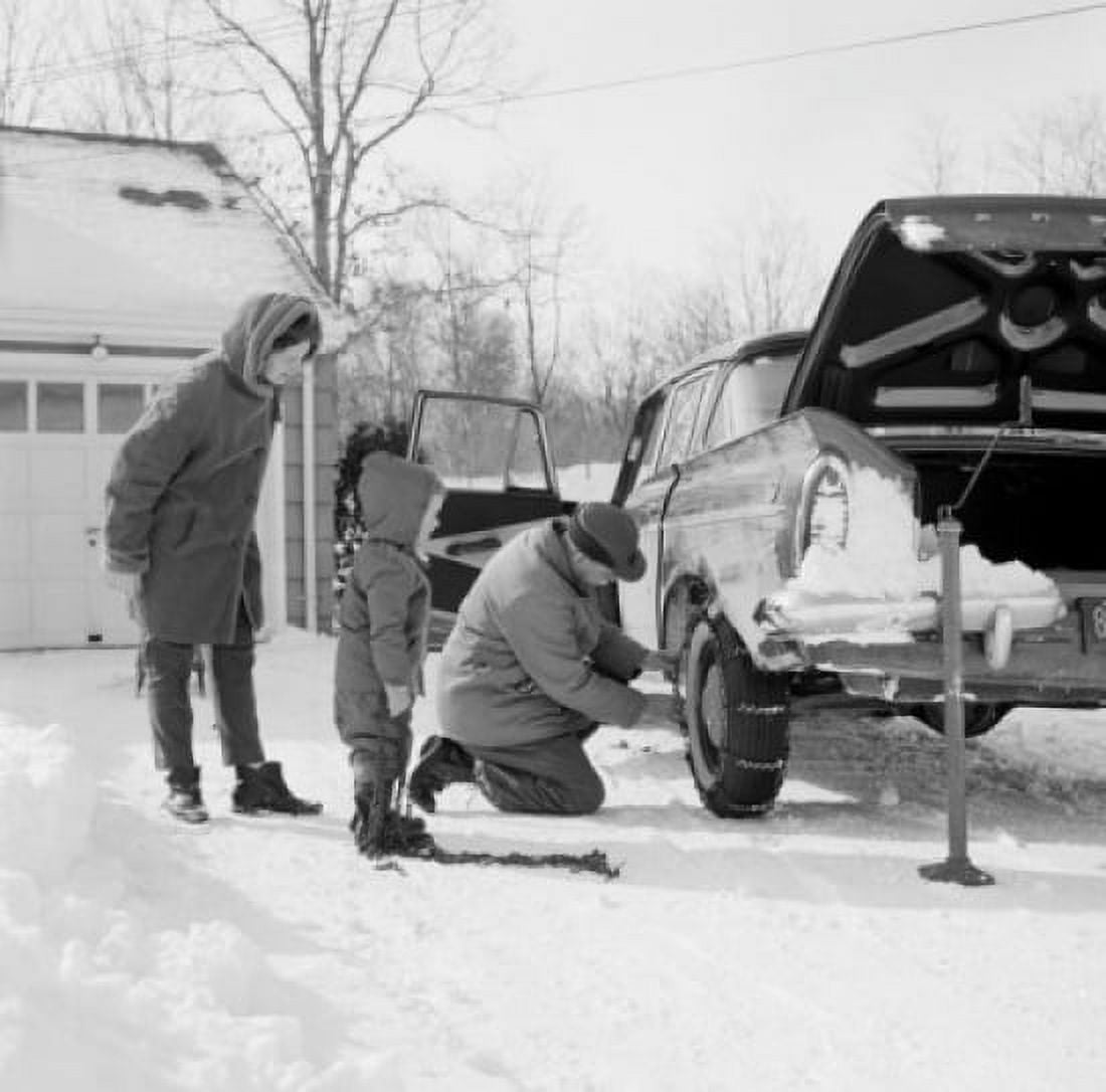 Man installing snow chain on cars wheel wife and son watching Canvas Art - (18 x 24)