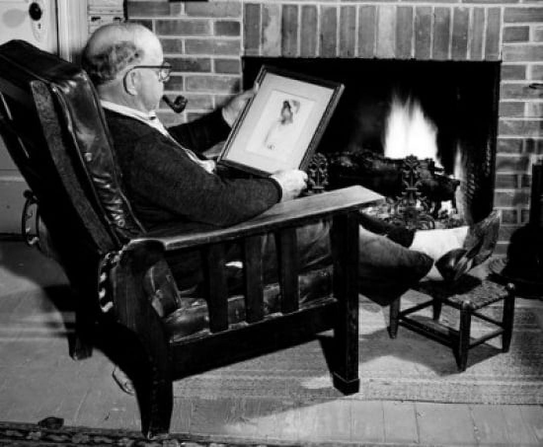 Man looking at old photograph by fireplace Canvas Art - (24 x 36)