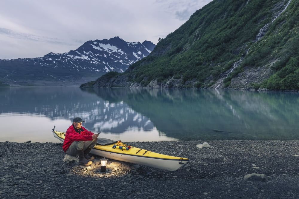 Man reading on a electronic tablet while camping with a kayak at Shoup Bay State Marine Park Prince William sound Valdez Southcentral Alaska Canvas Art - Kevin Smith Design Pics (38 x 24)
