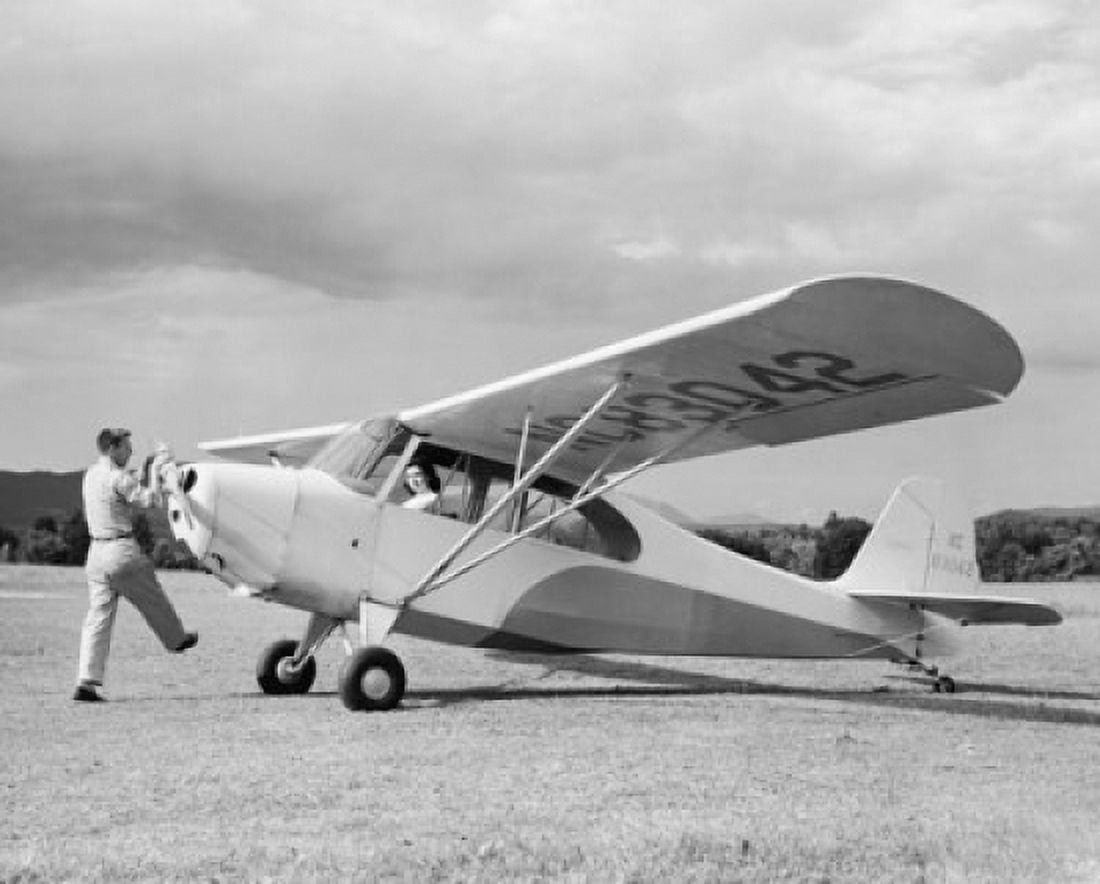 Man rotating the propeller of a private plane with a woman sitting in it Canvas Art - (18 x 24)