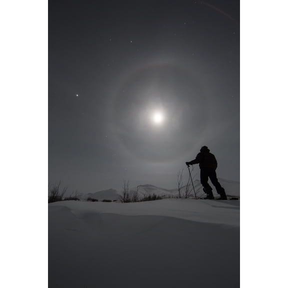 Man snowshoeing along the Dempster Highway under a moon glowing with rings Yukon Canada Canvas Art - Robert Postma Design Pics (12 x 19)