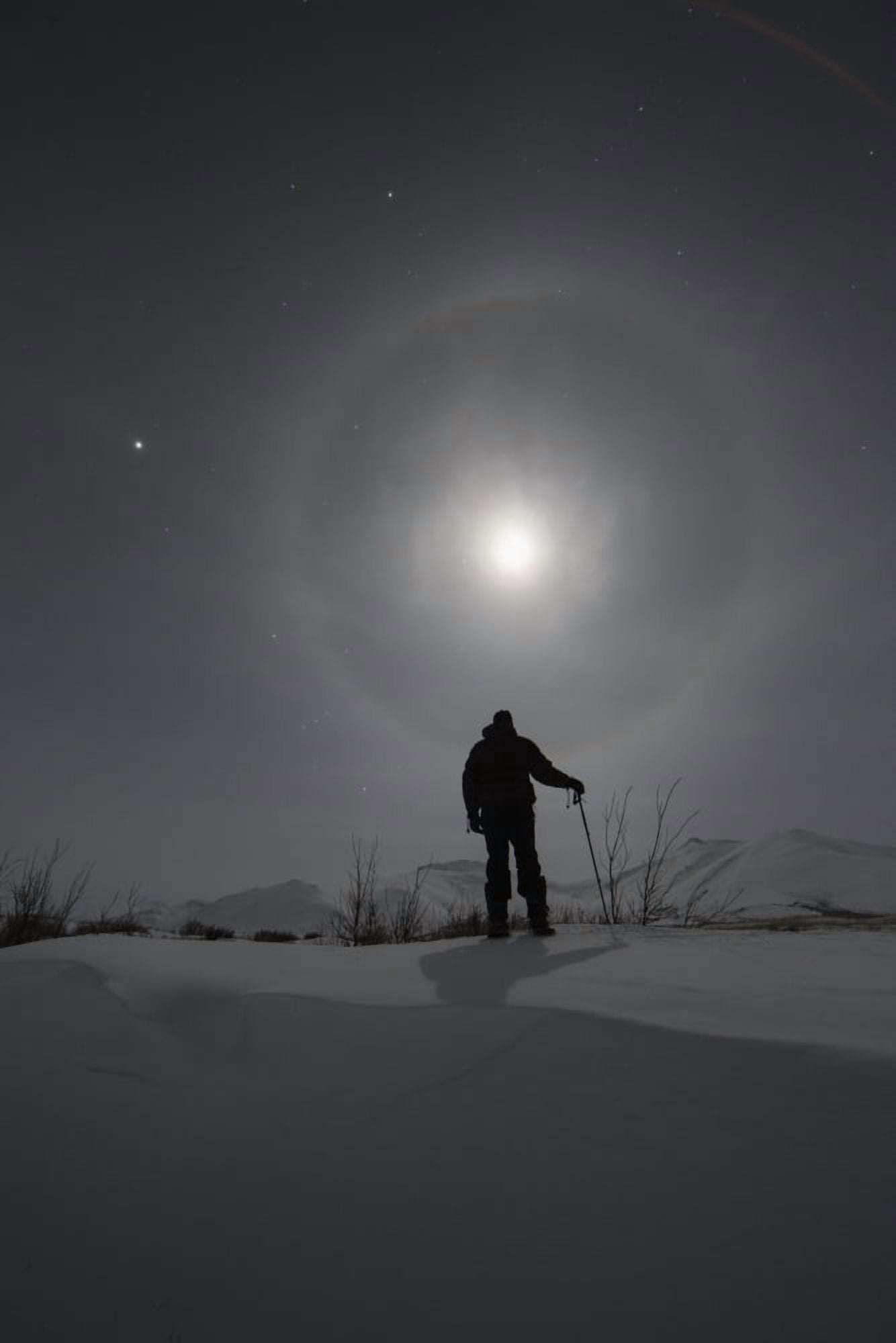 Man snowshoeing along the Dempster Highway under a moon glowing with rings Yukon Canada Canvas Art - Robert Postma Design Pics (12 x 19)