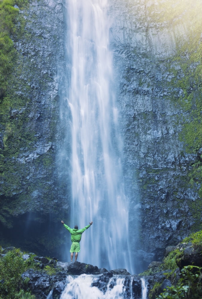 Man standing at the base of large waterfall in Hawaii Canvas Art - Design Pics Vibe Design Pics (11 x 16)