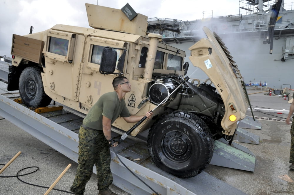 Marine uses a pressure washer to clean the underside of a Humvee hood Canvas Art - Stocktrek Images (35 x 23)
