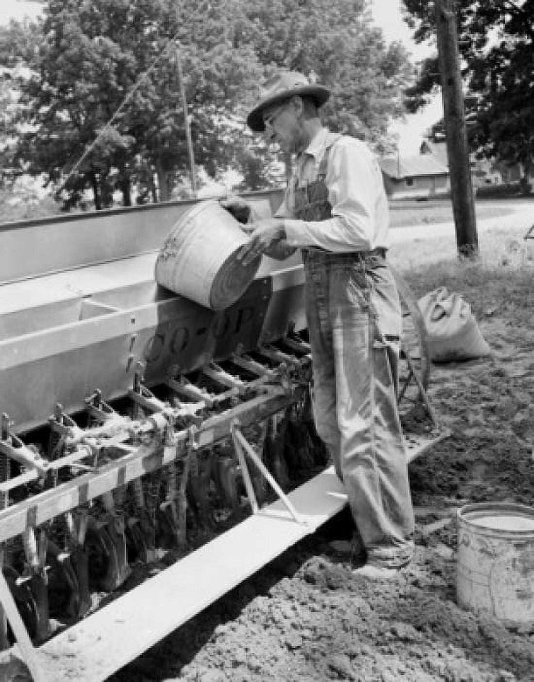 Mature man loading grinds into sowing machine Canvas Art - (18 x 24)