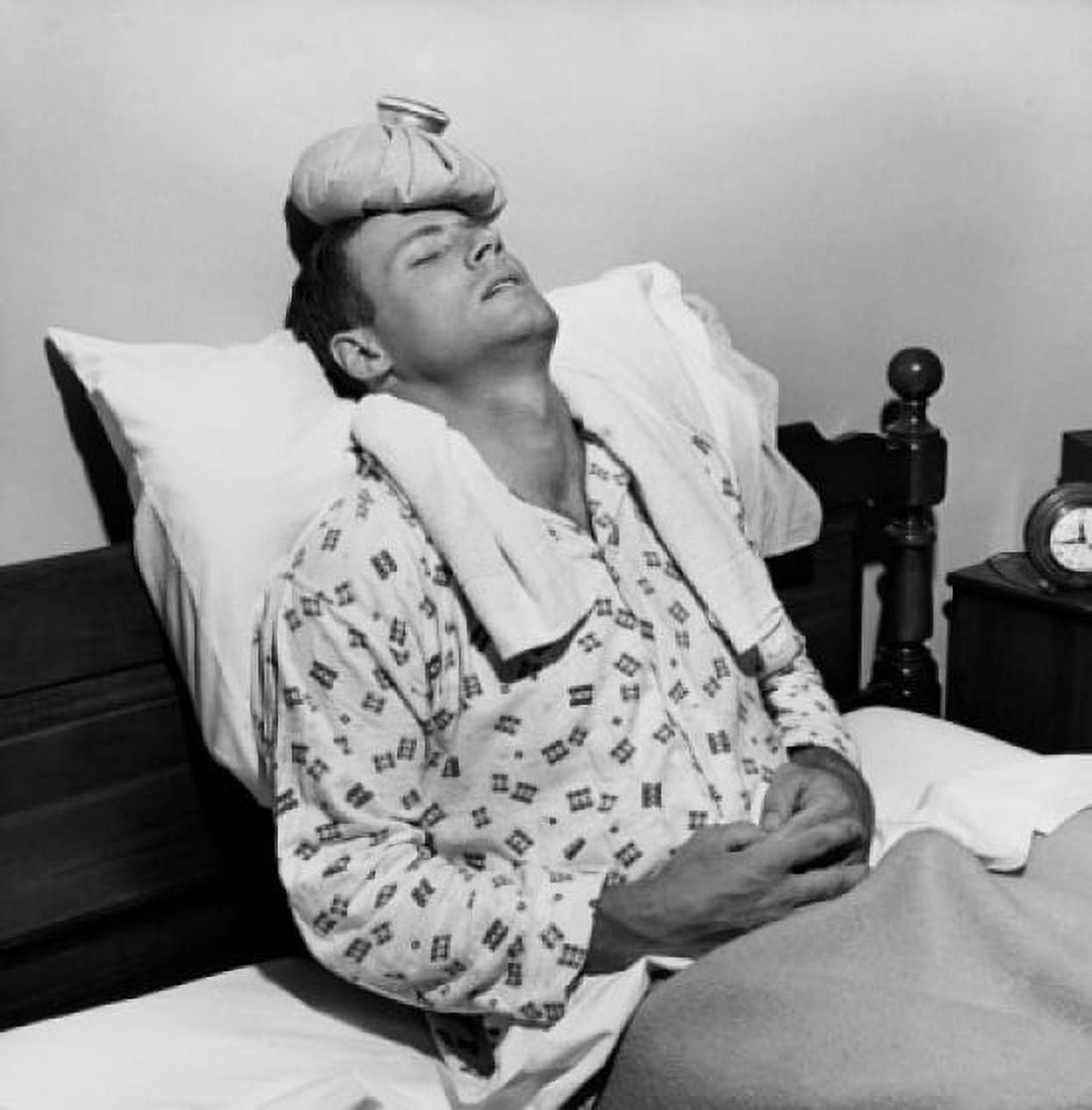 Mature man reclining on the bed with an ice pack on his head Canvas Art - (24 x 36)