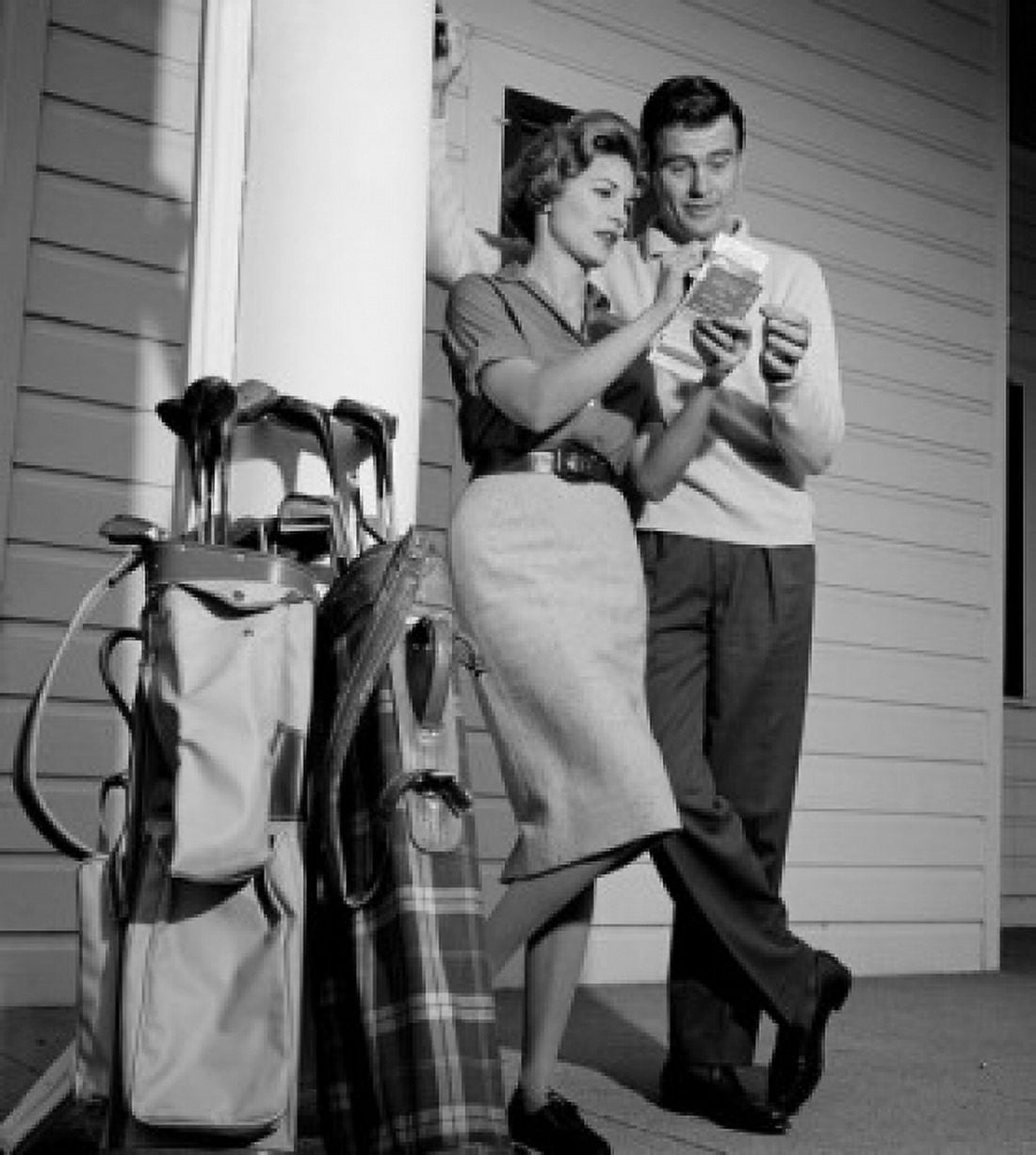 Mid-adult couple examining tickets with golf trolleys standing against column Canvas Art - (24 x 36)
