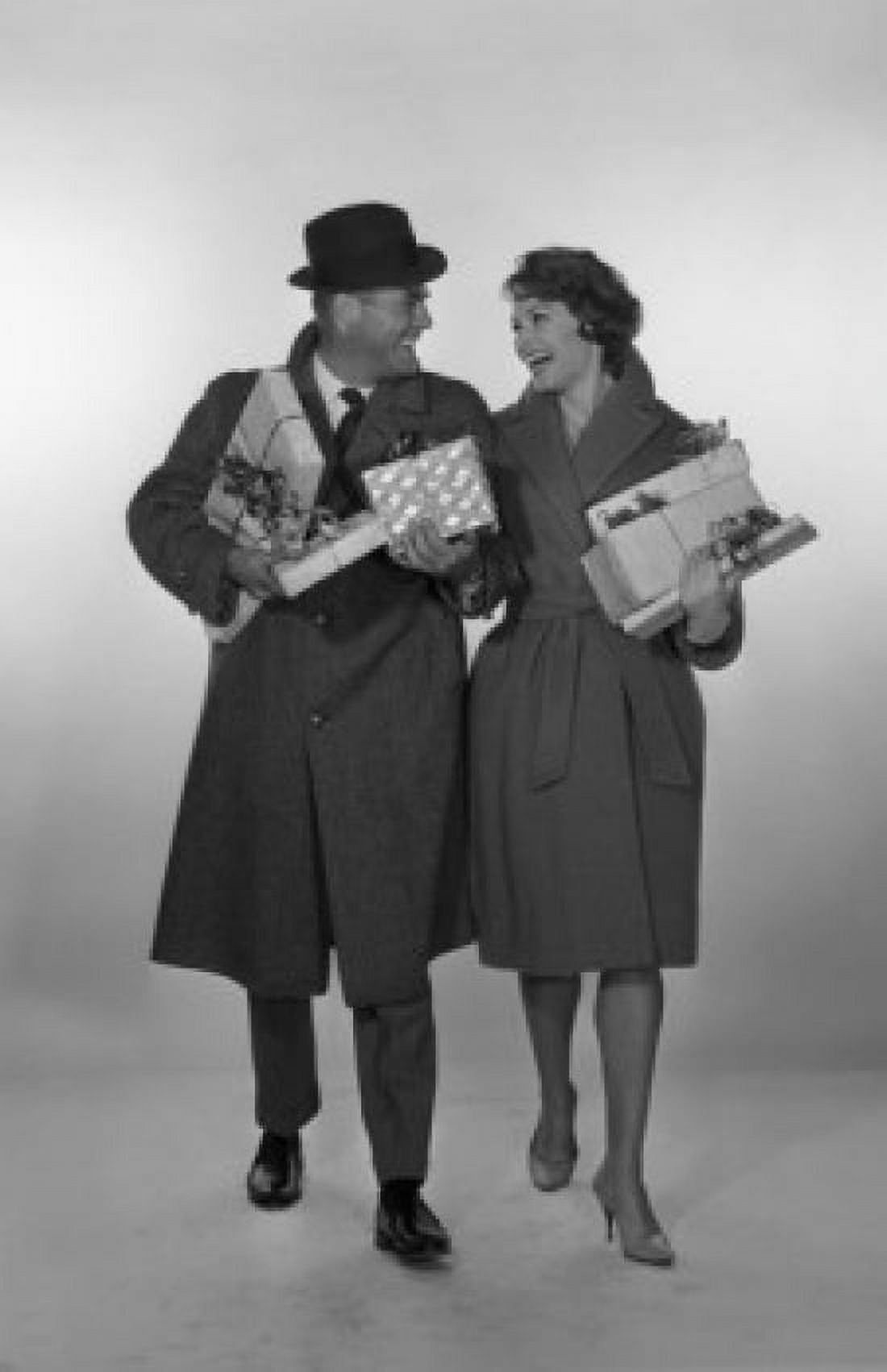 Mid adult couple laughing looking at each other and holding gifts studio shot Canvas Art - (18 x 24)