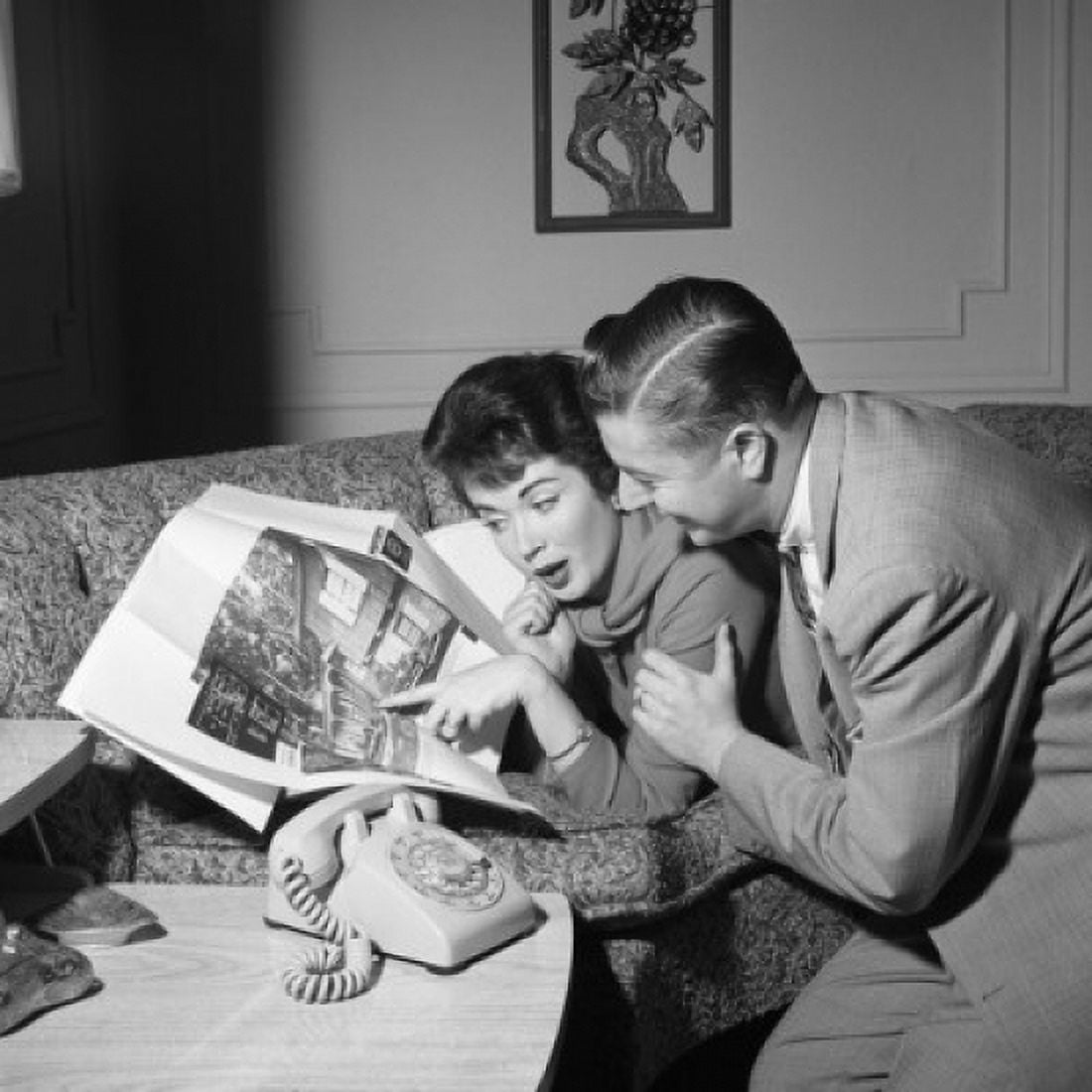 Mid adult couple looking at photograph in magazine Canvas Art - (18 x 24)