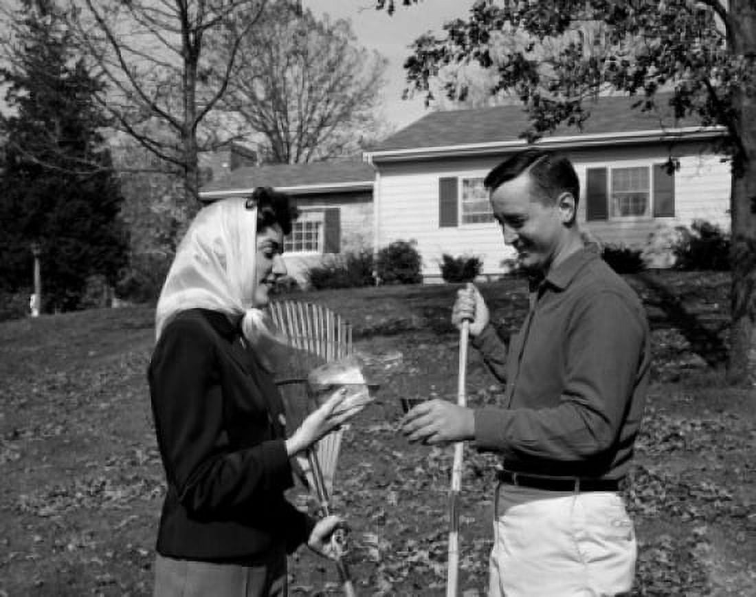 Mid adult couple with racks standing on lawn preparing for raking autumn leaves from lawn Canvas Art - (24 x 36)