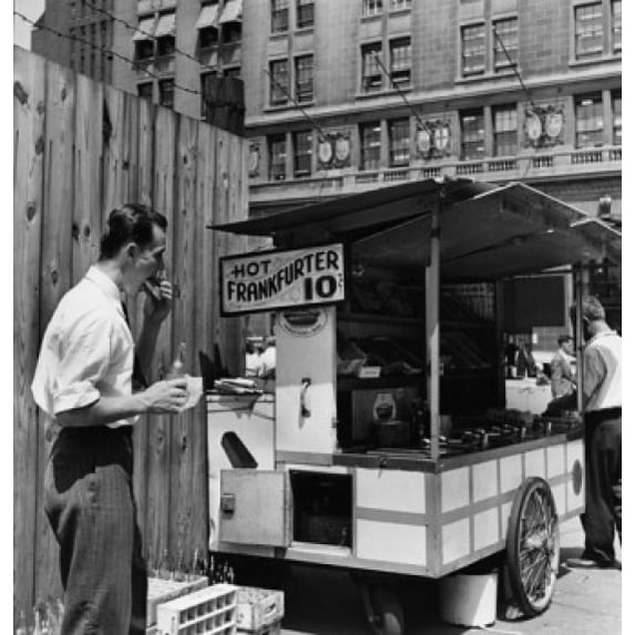 Mid adult man eating food near a hot dog stand, New York City, New York, USA Poster Print (24 x 36)