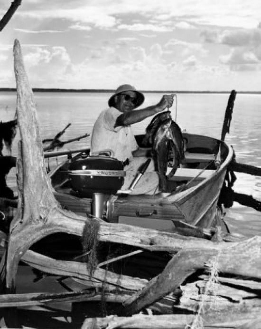 Mid adult man sitting on a motorboat and holding dead fish Canvas Art - (18 x 24)
