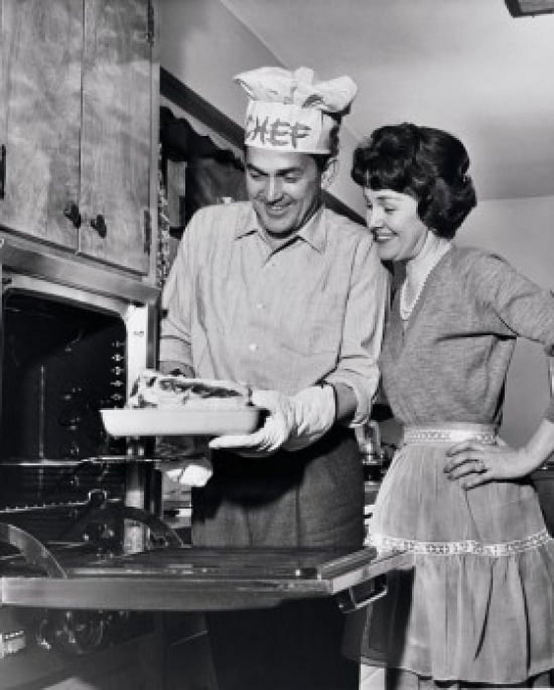 Mid adult man taking food out of an oven with a mid adult woman standing beside him Canvas Art - (18 x 24)