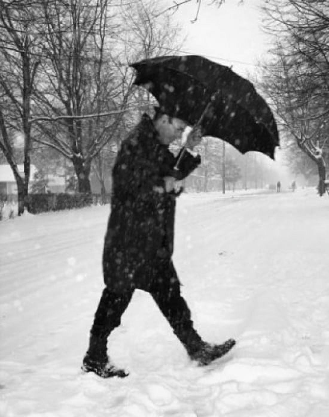 Mid adult man walking on snow covered road with umbrella Canvas Art - (18 x 24)