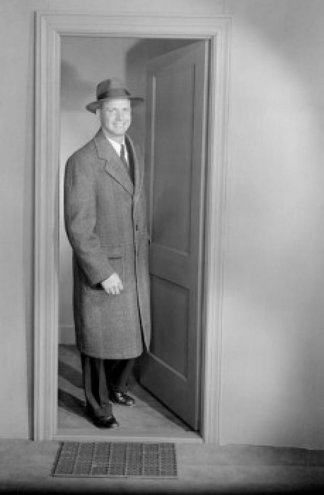 Mid adult man wearing overcoat and hat emerging from door Canvas Art - (24 x 36)
