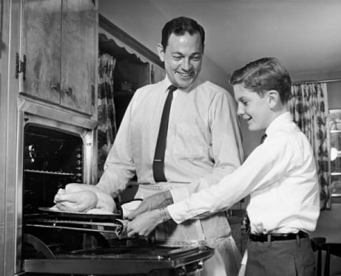 Mid adult man with his son putting a turkey into an oven Canvas Art - (24 x 36)