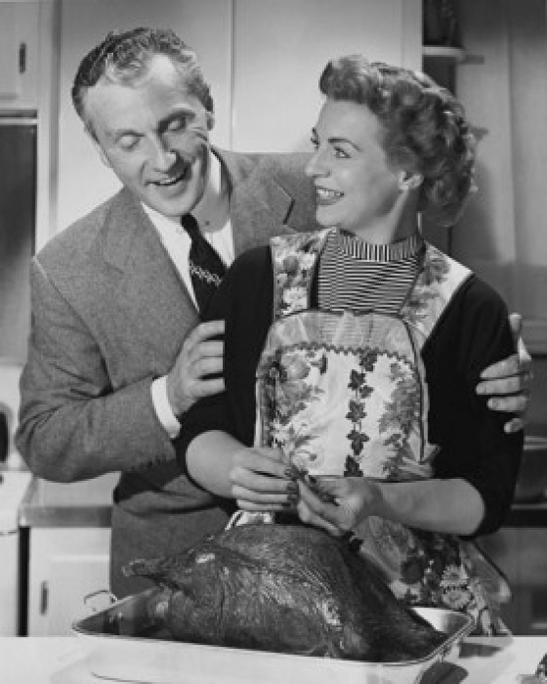 Mid adult man woman preparing a turkey and a mid adult man holding her from behind Canvas Art -  (24 x 36)