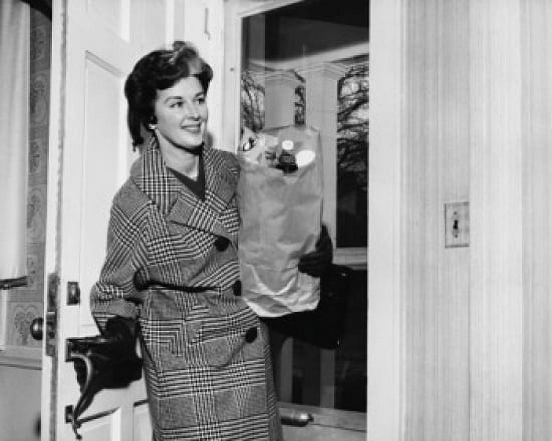 Mid adult woman holding a paper bag and entering a room Canvas Art - (18 x 24)