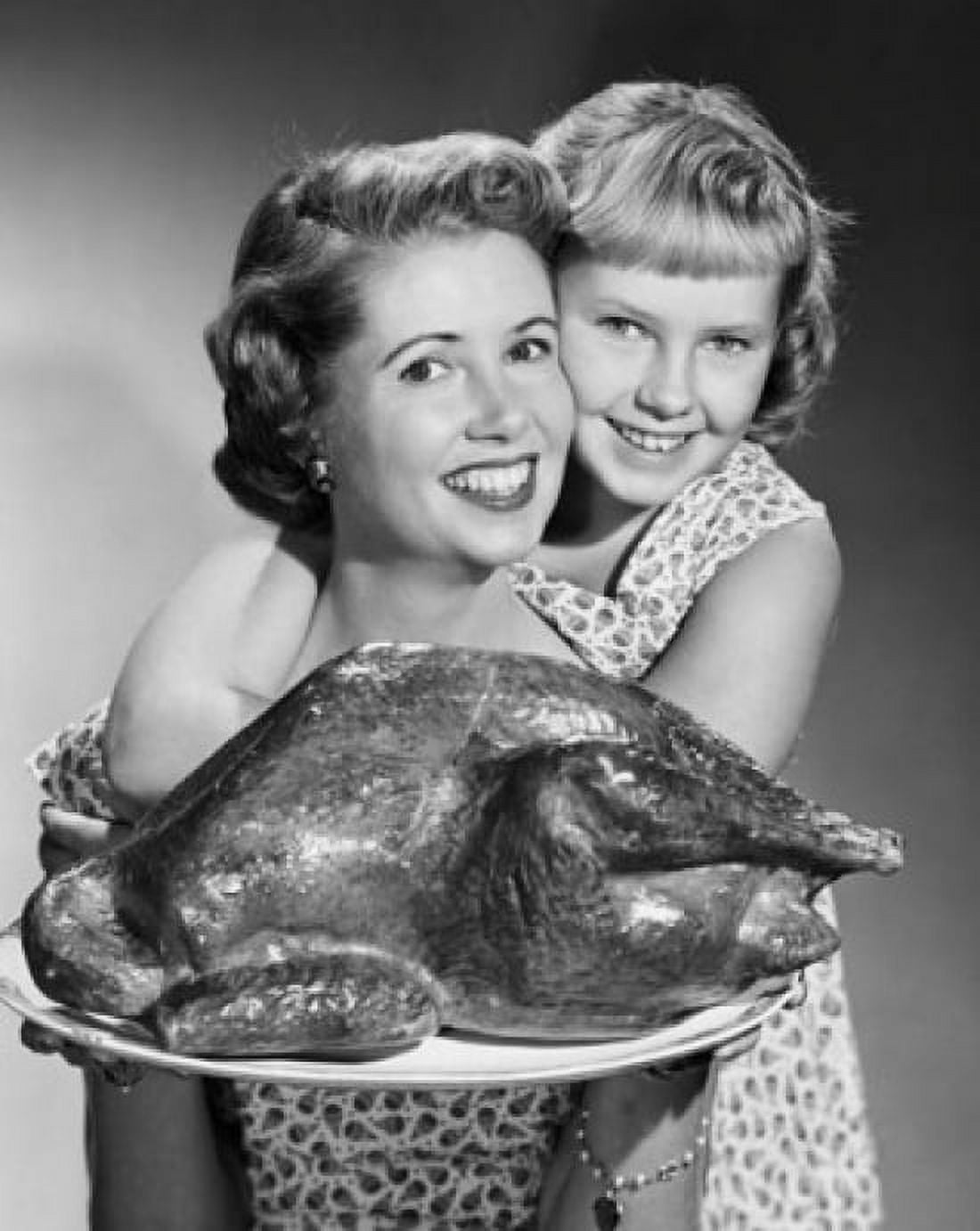 Mid adult woman holding roasted turkey on a tray with her daughter hugging her from behind Canvas Art - (18 x 24)