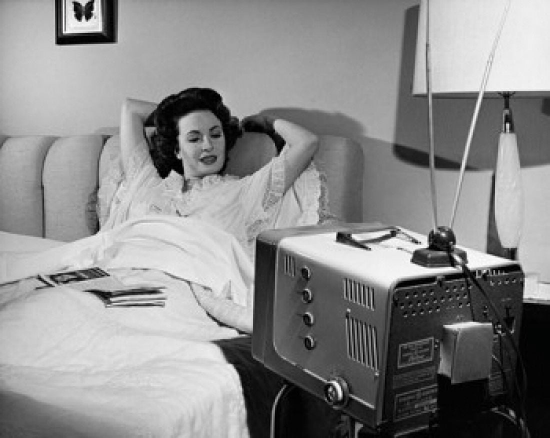 Mid adult woman lying on the bed watching television Canvas Art - (18 x 24)