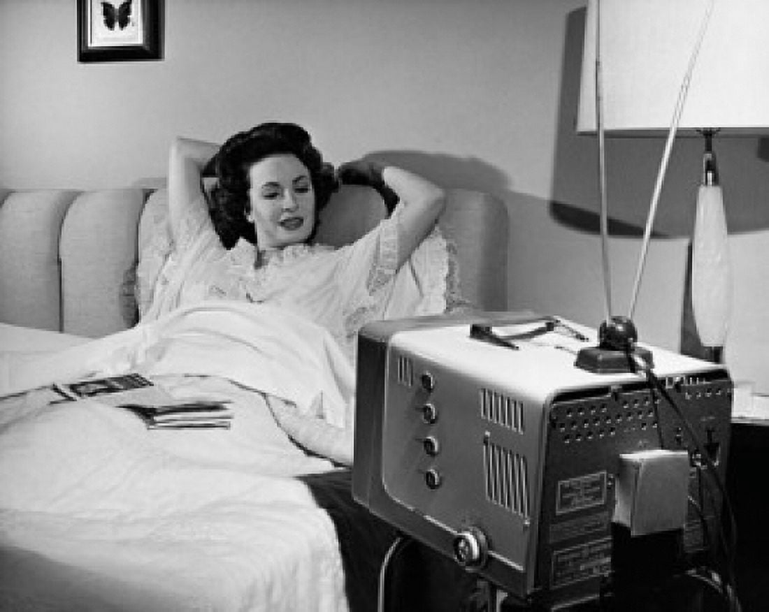 Mid adult woman lying on the bed watching television Canvas Art - (24 x 36)