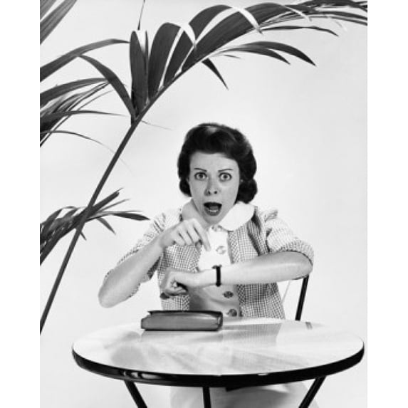 Mid adult woman pointing to her wristwatch and looking angry Poster Print (18 x 24)