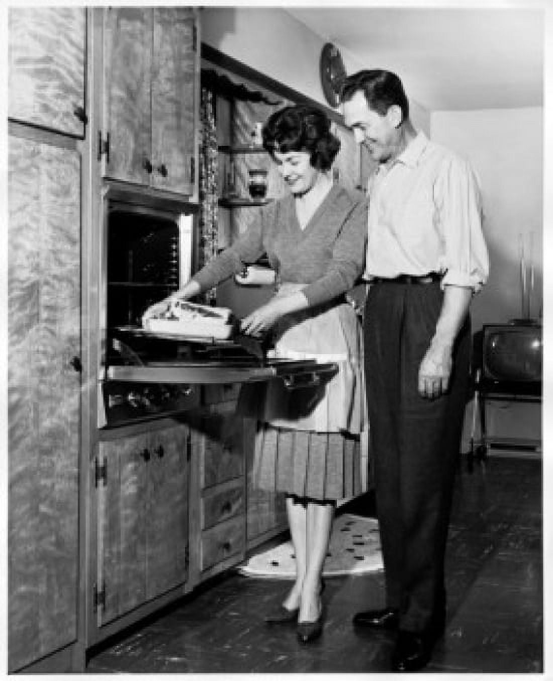 Mid adult woman putting food into an oven with a mid adult man standing beside her Canvas Art - (24 x 36)