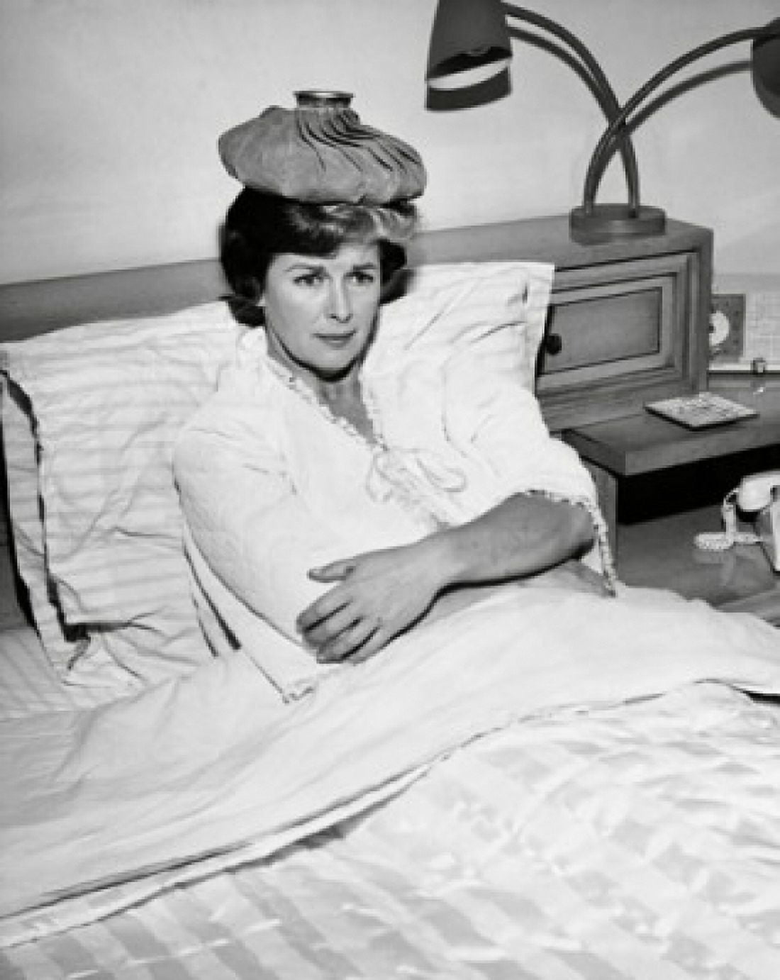 Mid adult woman reclining on the bed with an ice pack on her head Canvas Art - (18 x 24)