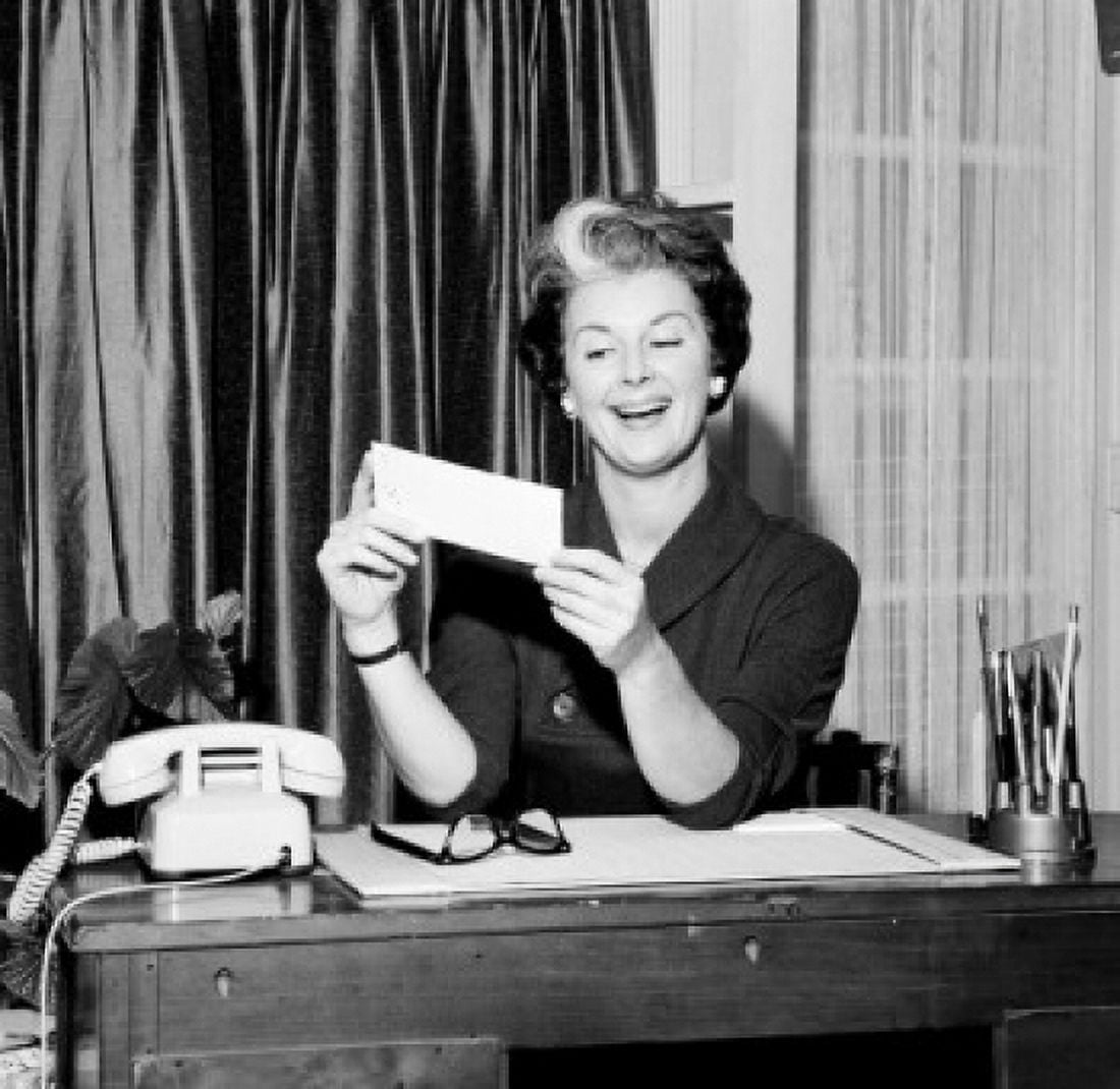 Mid adult woman sitting at desk and holding paycheck Canvas Art - (24 x 36)