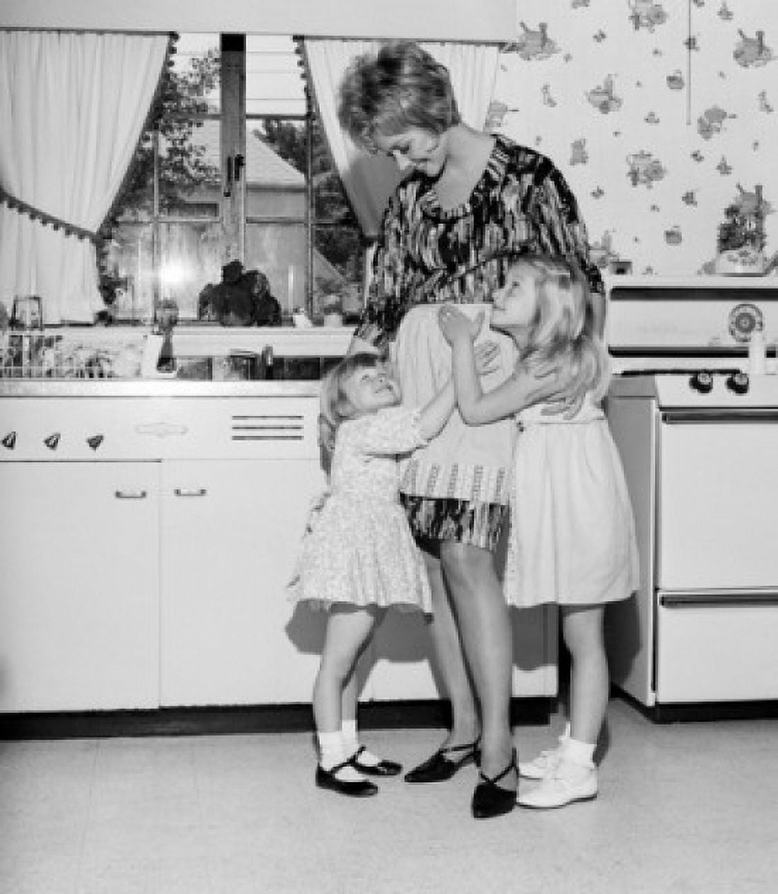 Mother embracing daughters in kitchen Canvas Art - (18 x 24)