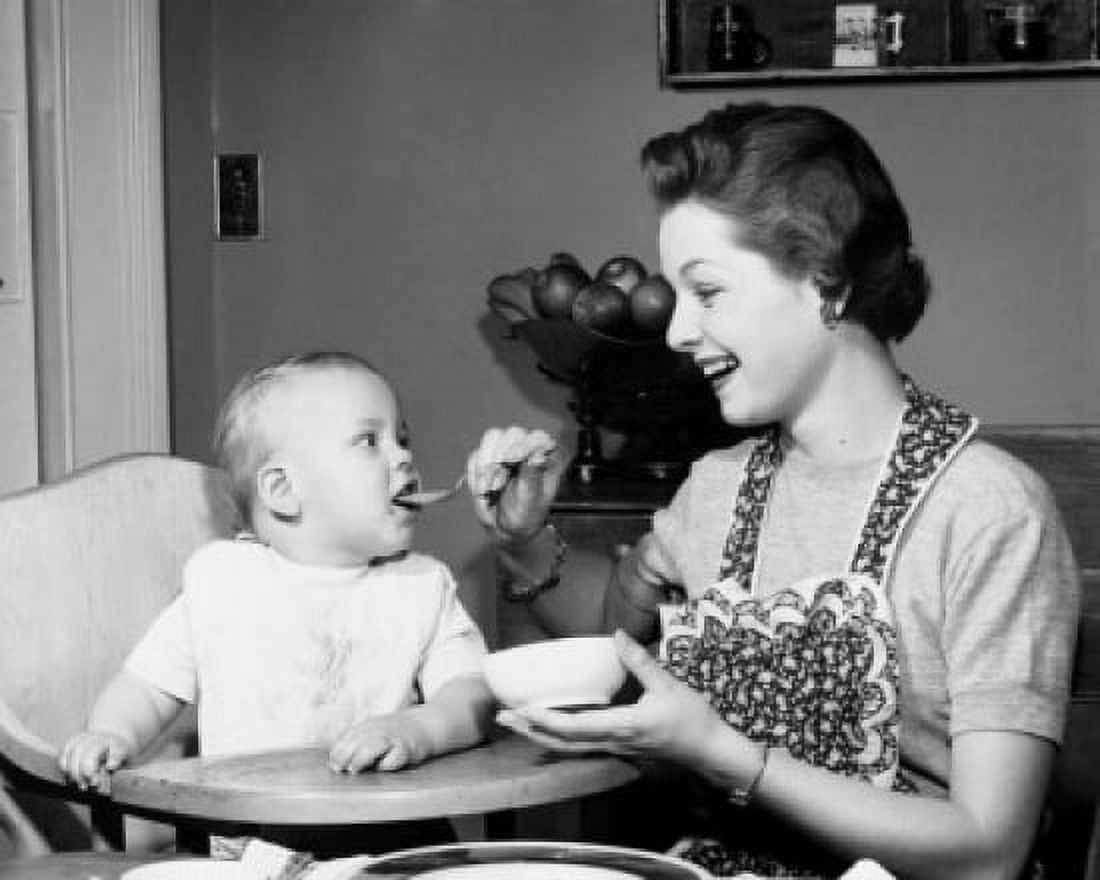 Mother feeding baby boy in high chair Canvas Art - (24 x 36)