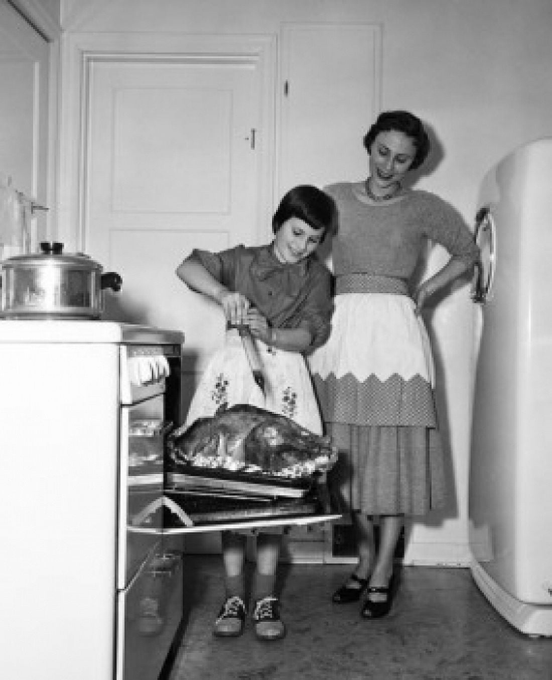 Mother looking at her daughter basting a turkey Canvas Art - (24 x 36)