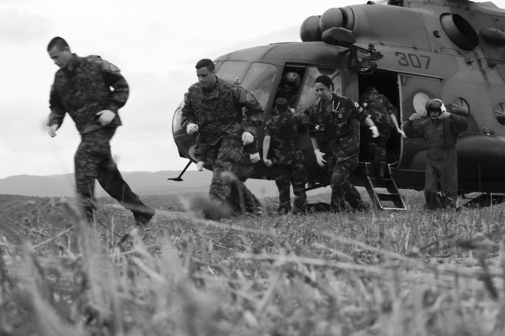 Multinational medical personnel retreat after loading a wounded patient onto a helicopter Canvas Art - Stocktrek Images (34 x 23)