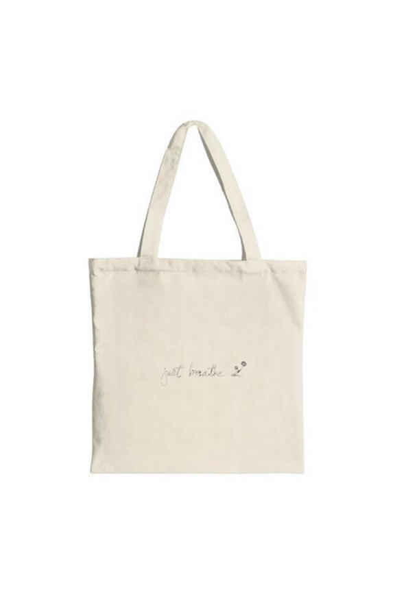 Natural canvas tote bag with sturdy handles featuring ' just breathe ' in handwritten style and small leaf doodles Perfect for shopping and travel