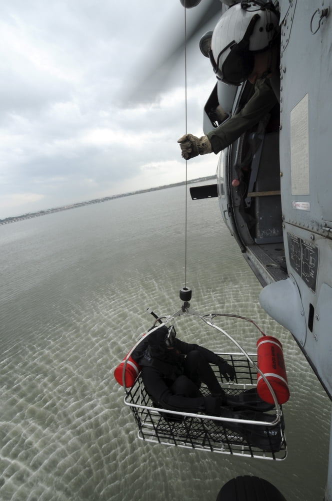 Naval Air Crewman hoists a rescue basket into an MH-60S Sea Hawk helicopter Canvas Art - Stocktrek Images (23 x 35)