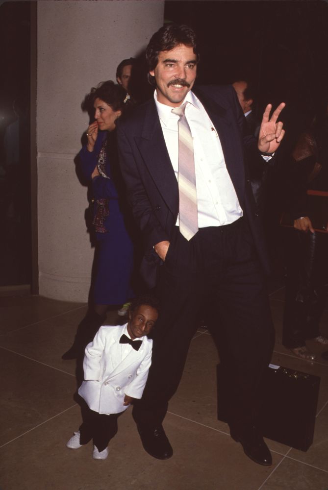 Nelson De La Rosa In White Tuxedo And Man Giving Peace Sign Photo Print (8 x 10) Item