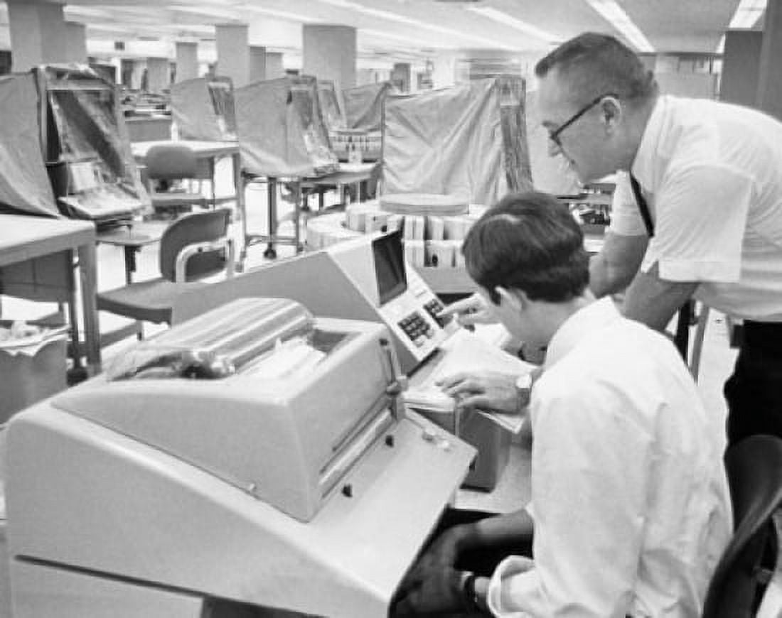 Office worker demonstrates the computer interrogation device for updating customer records Canvas Art - (18 x 24)