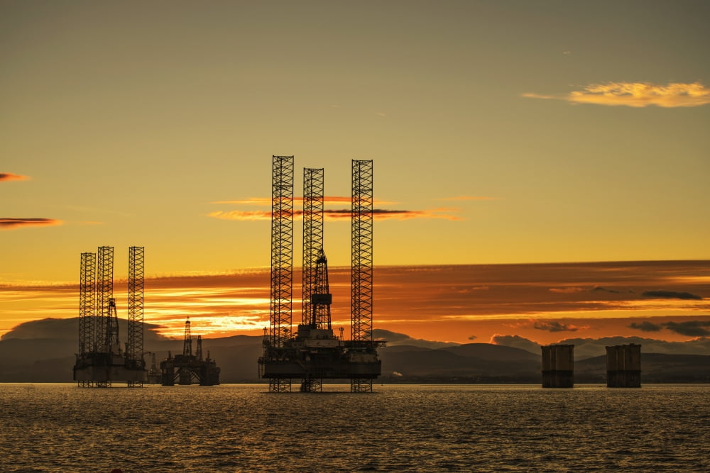 Oil drilling rigs out in the ocean with a view of the coastline and golden sunset Cromarty Invergordon Scotland Canvas Art - John Short Design Pics (19 x 12)