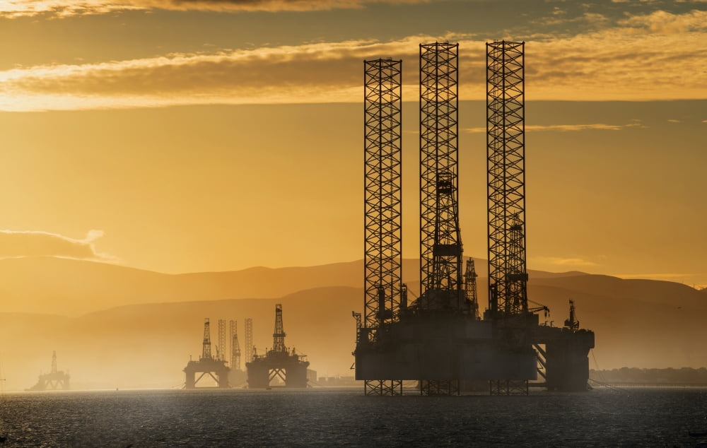 Oil drilling rigs out in the ocean with a view of the coastline and golden sunset Cromarty Invergordon Scotland Canvas Art - John Short Design Pics (19 x 12)